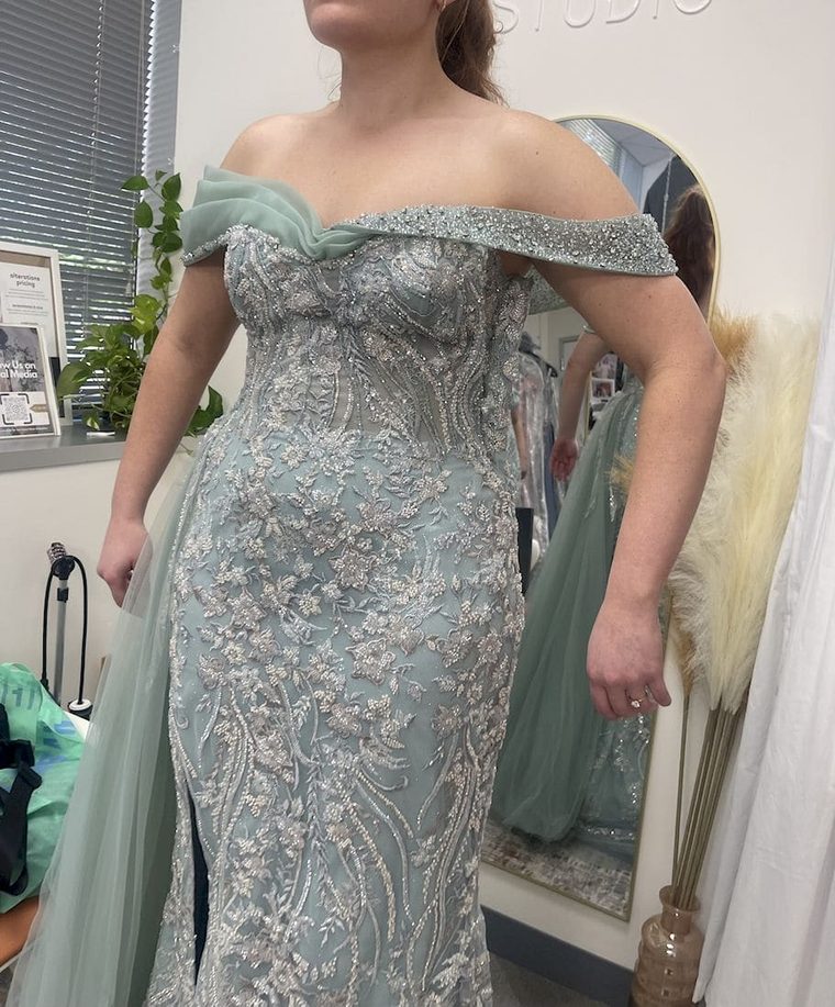 A client wearing a sage green beaded gown during a fitting in the Sharifi's Studio workroom in Vienna.
