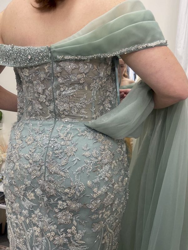 Close detail of the beaded bodice and centre back seam of a sage green gown during fitting.
