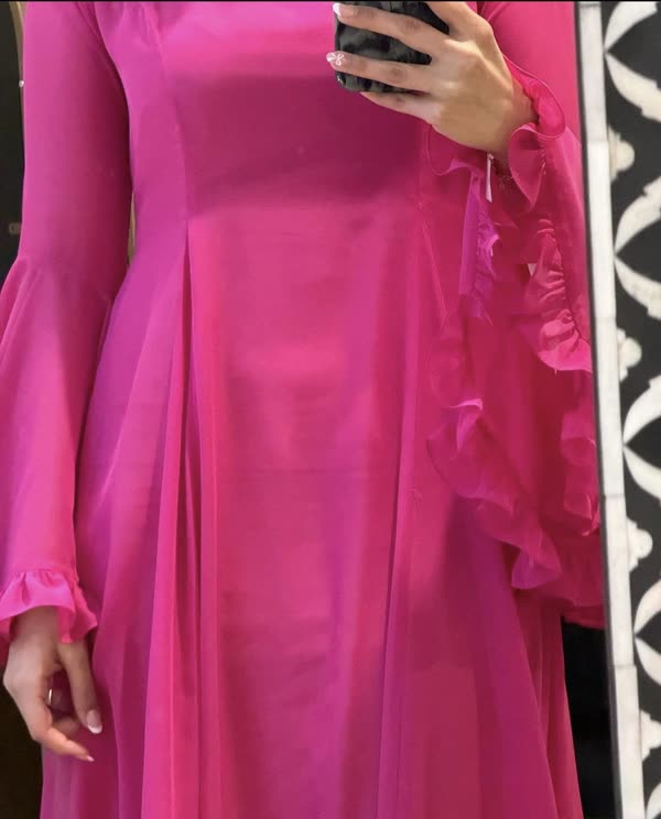 A finished magenta silk dress worn in the studio, showing the flared cuff and ruffled front panel.