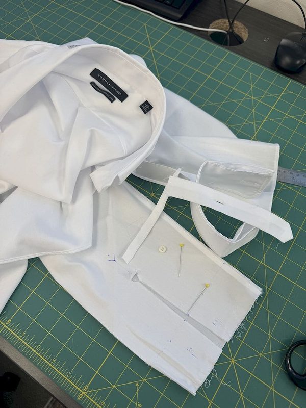 A white shirt opened out on the cutting mat, sleeve panel pinned and marked ready for alteration.